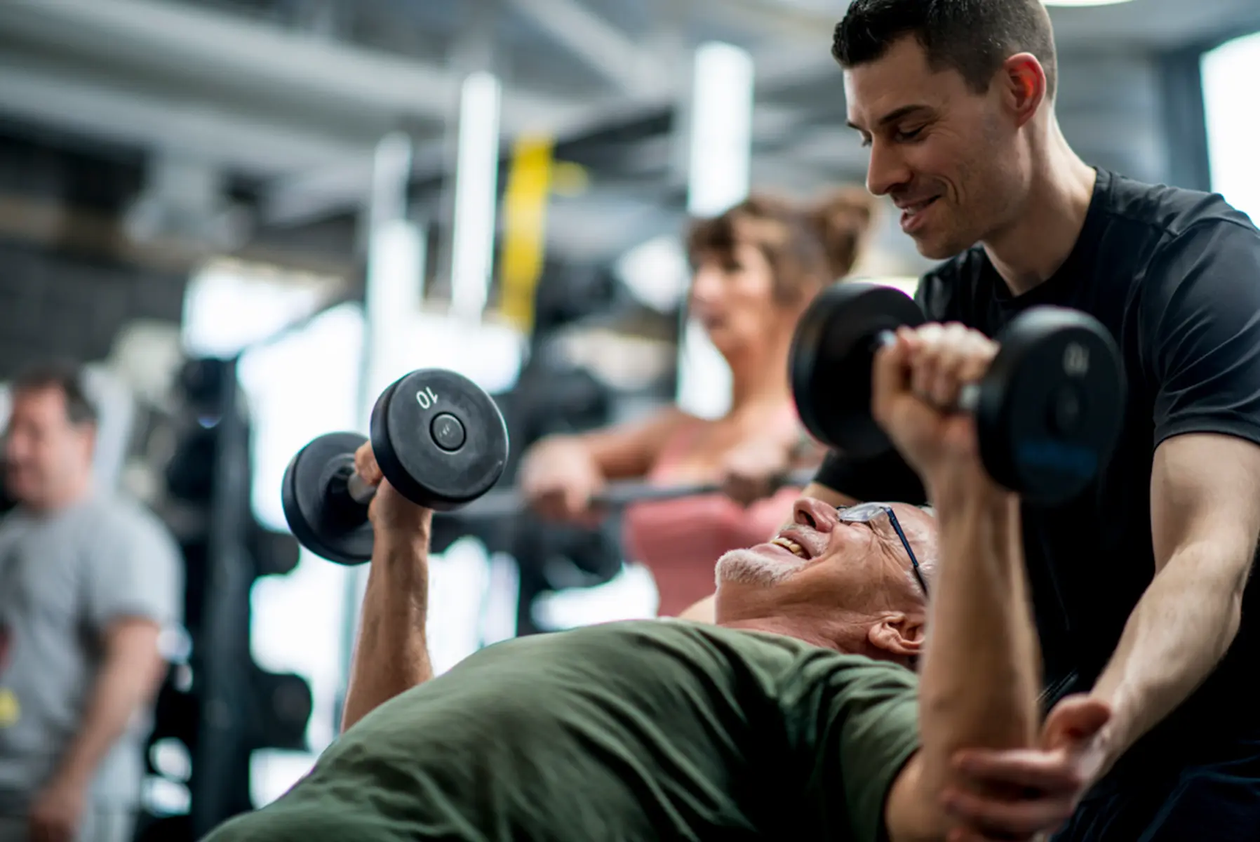 Masters lifter being coached in dumbbell chest press
