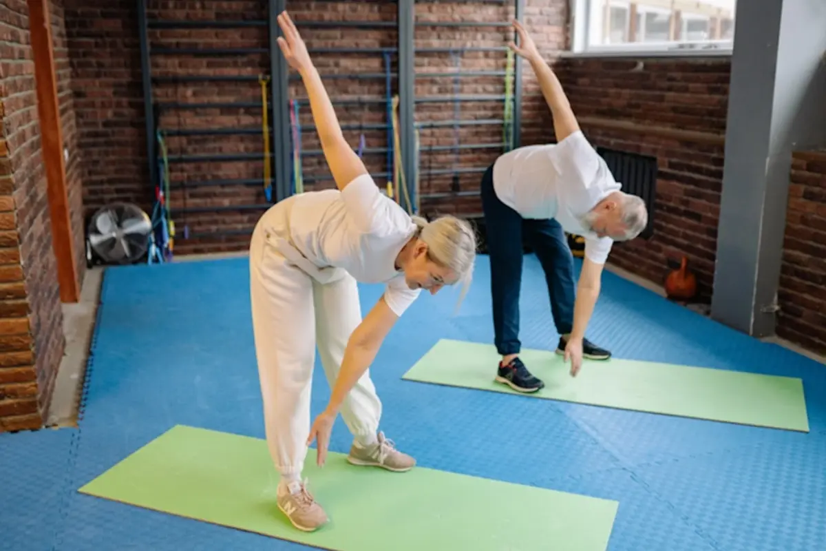 Older woman and man doing a dynamic warm-up in the gym