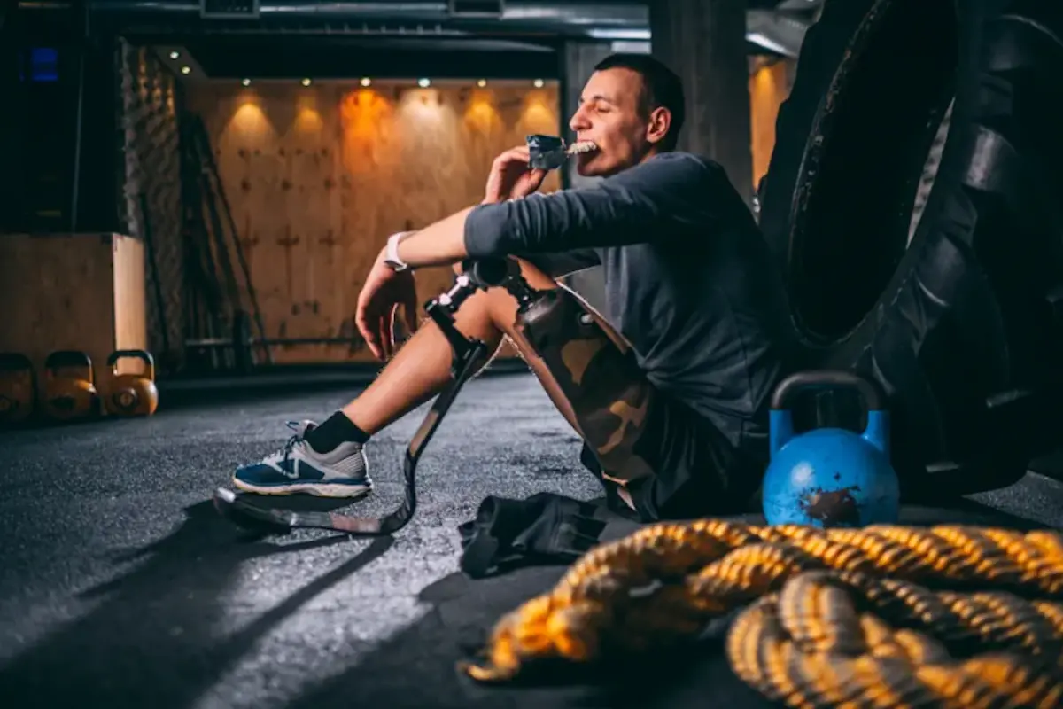 A man seated in the gym eating a snack