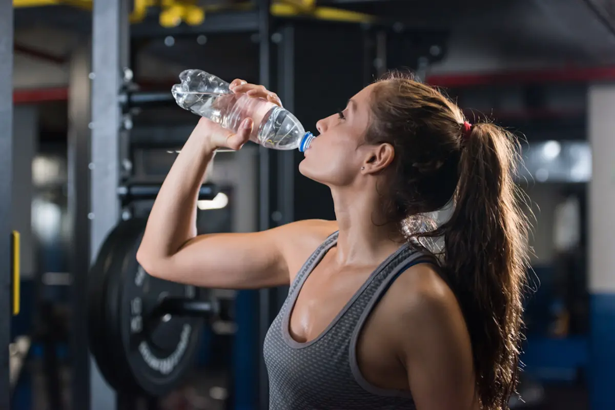 Woman drinking water in the gym