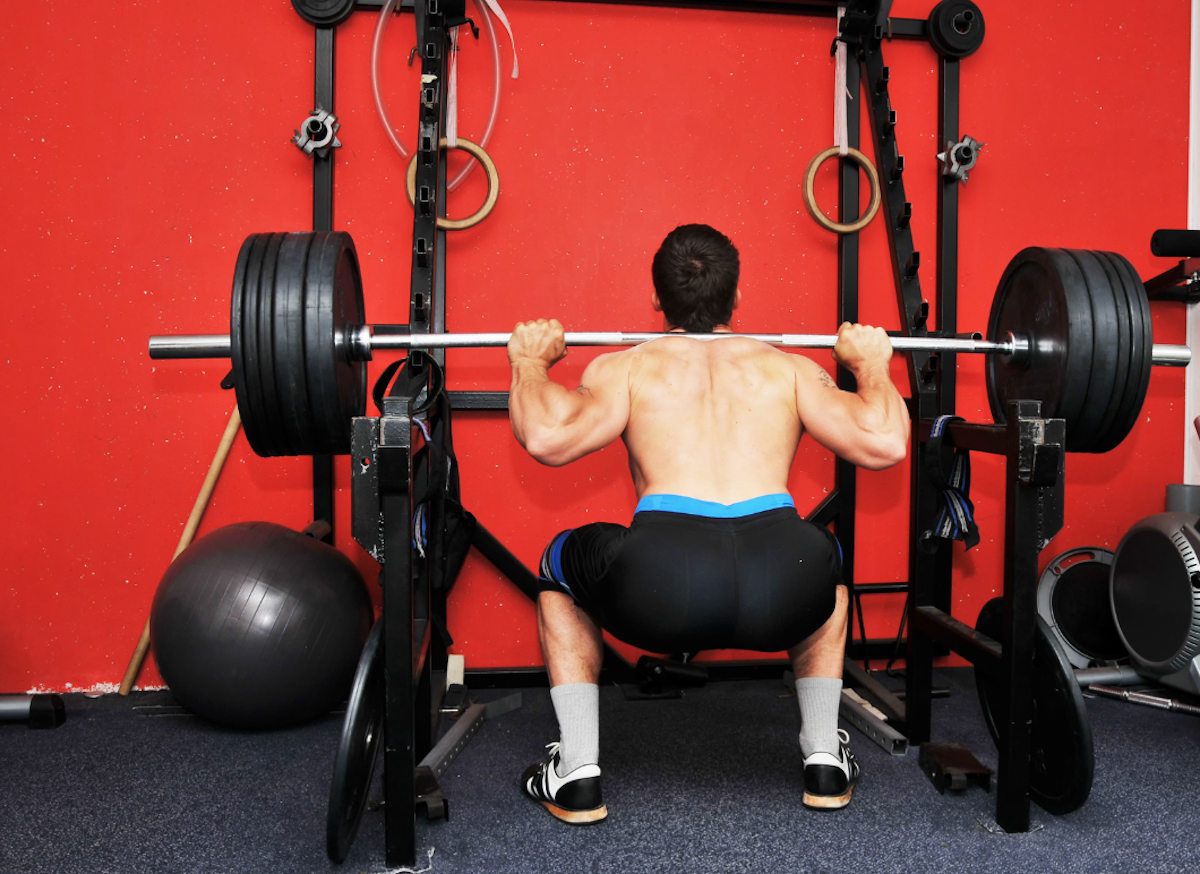 Man at the bottom of a barbell back squat