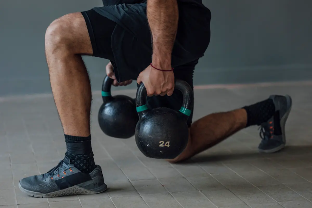 Close-up of split squat with kettlebells
